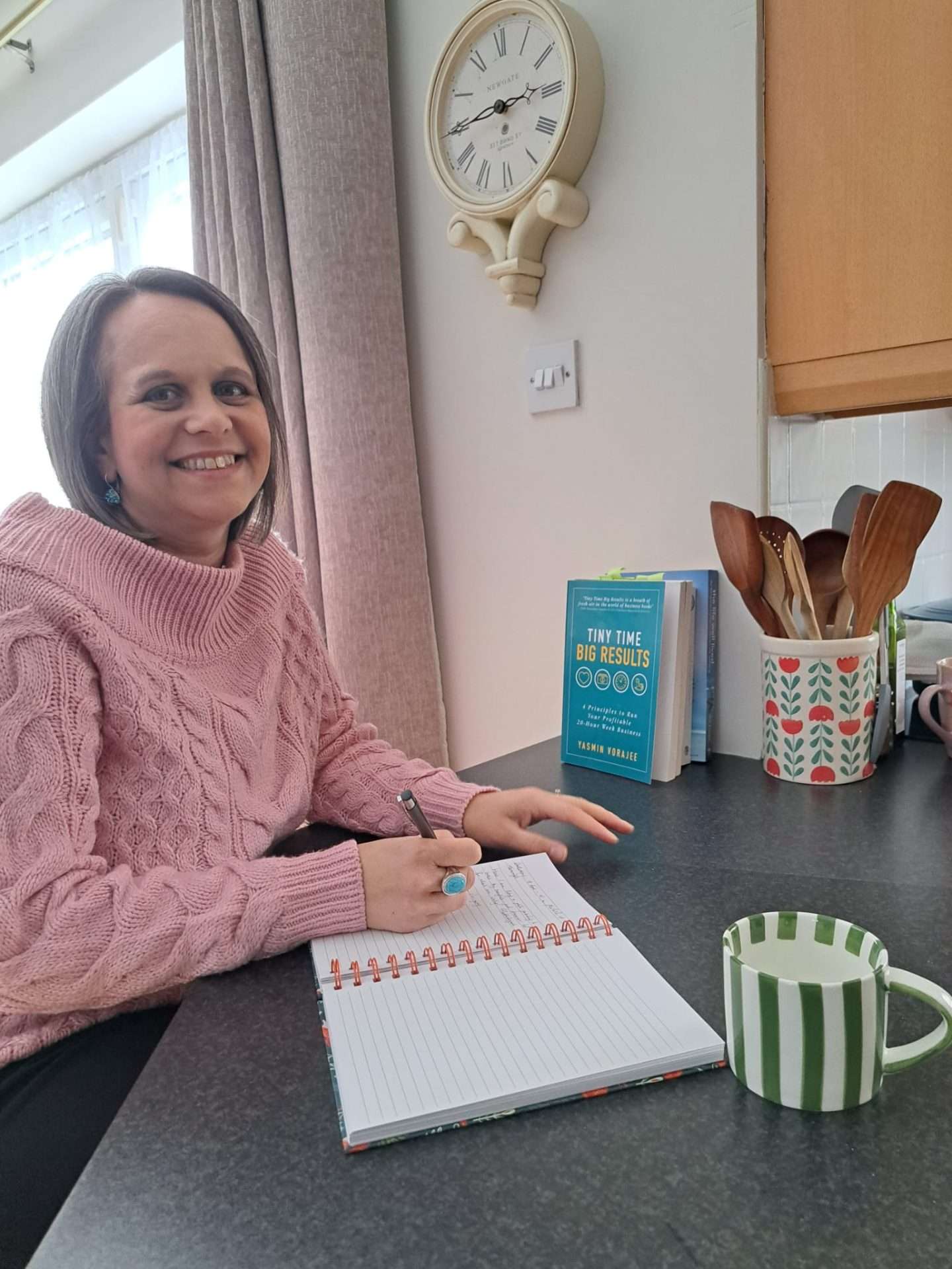 Yasmin Vorajee writing in her planner with her book, Tiny Time Big Results